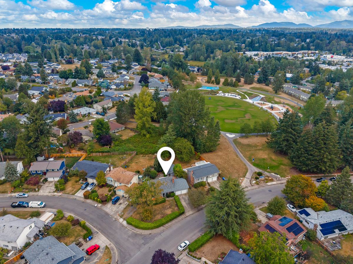 Aerial view of the home, marked with a location pin, beside a park with a large lawn, playground, and sport court