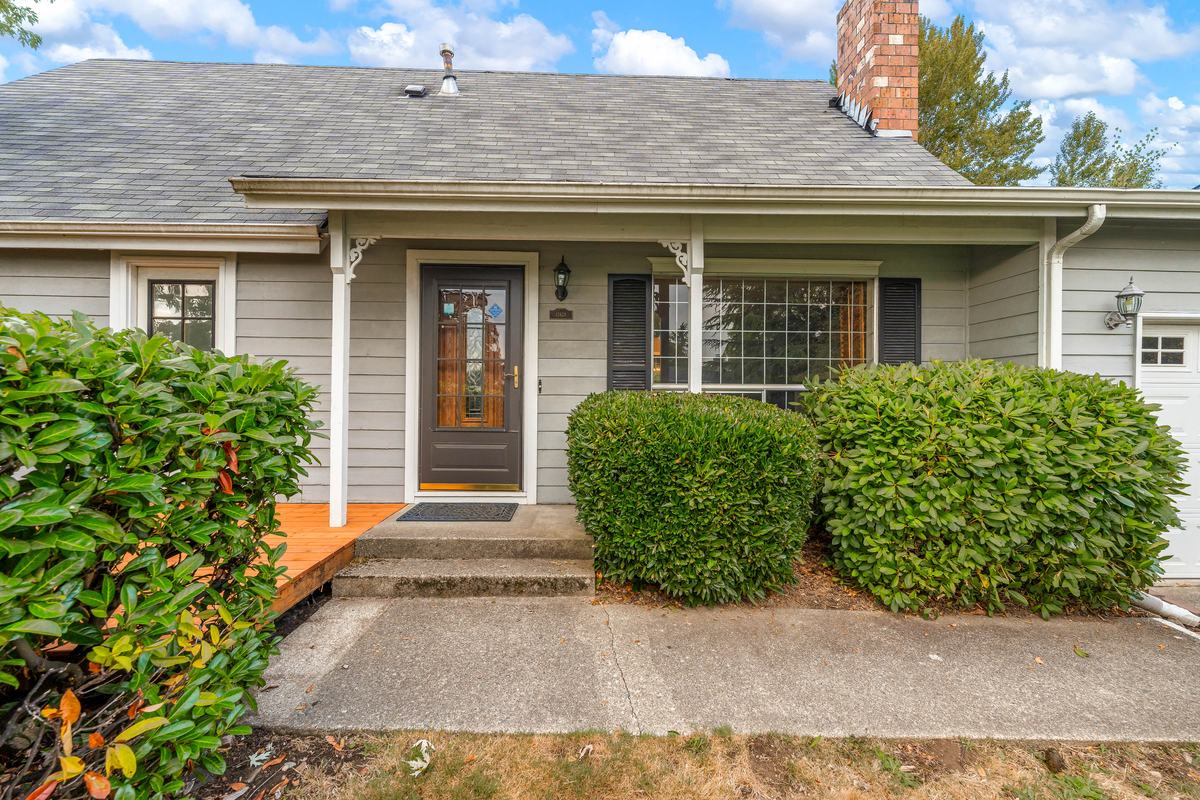 Front of the home at 12628 SE 276th Pl with its covered porch, new cedar deck, and mature shrubs